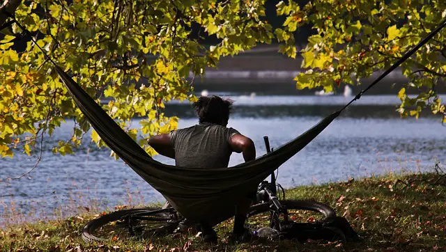 man sitting on a hammock along a river